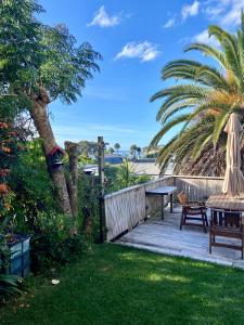 a patio with a table and chairs and a palm tree at Palm Garden Apartment in Auckland