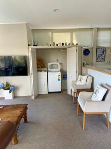 ein Wohnzimmer mit einem Tisch und Stühlen sowie eine Küche in der Unterkunft Palm Garden Apartment in Auckland