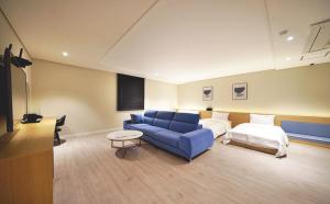 sala de estar con sofá azul y cama en Hotel LeeSunDeok en Busan