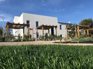 a white building with wooden structures in front of a yard at Tavira-Quinta da Janela Azul in Tavira