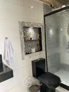a bathroom with a black toilet and a shower at Pousada do Mirante do Atalaia in Arraial do Cabo
