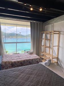 a bedroom with two beds and a large window at Pousada do Mirante do Atalaia in Arraial do Cabo