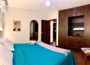 sypialnia z niebieskim łóżkiem i telewizorem w obiekcie Ciprés Confort w mieście Santa Cruz de la Sierra