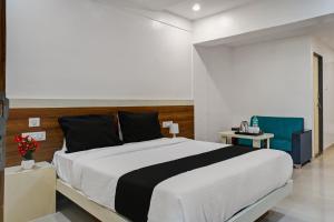 a bedroom with a large bed and two blue chairs at Collection O Hotel Stay Prime Baner in Pune