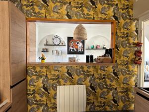 een woonkamer met een gele muur met een spiegel bij La Maison des Rochettes in Flers