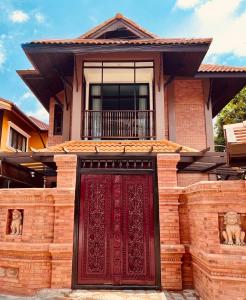 uma casa com uma porta vermelha em frente em Phor Liang Meun Terracotta Arts em Chiang Mai