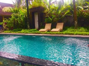 a pool with two lounge chairs next to a house at Villa Mahesa in Ubud