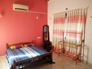 - une chambre avec un lit et un mur rouge dans l'établissement SHERMILAS BUNGLOW, à Hambantota
