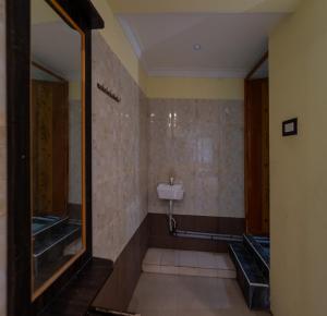 a bathroom with a urinal and a mirror at JR Lodge in Velankanni