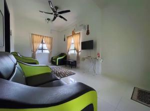 a living room with green chairs and a ceiling fan at Wans Farm House in Kuala Besut