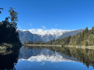a reflection of snow capped mountains in a lake at Fox Glacier Lodge in Fox Glacier