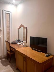 Habitación con escritorio, TV y espejo. en Madella Hotel, en Can Tho
