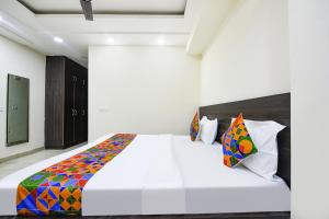FabHotel Dwarka Residency في نيودلهي: غرفة نوم مع سرير أبيض كبير مع وسائد ملونة