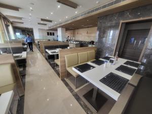 um restaurante com mesas e uma pessoa ao fundo em Grand Continent Hosur A Sarovar Portico Affiliate Hotel em Hosur