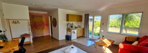 a living room with a red couch and a kitchen at Peace and Aroha Mangawhai - Apartment in Mangawhai