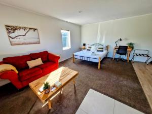 a living room with a red couch and a table at Peace and Aroha Mangawhai - Apartment in Mangawhai
