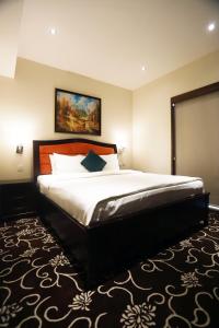 فندق Naylover Suites في عمّان: غرفة نوم بسرير كبير عليها لوحة على الحائط