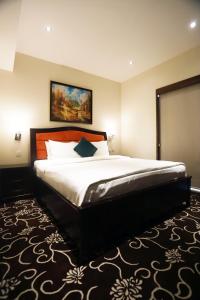 a bedroom with a large bed with a painting on the wall at Naylover Hotel Suites in Amman