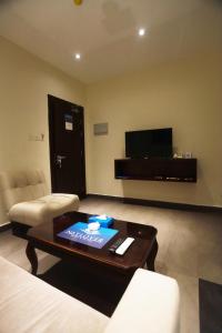 ein Wohnzimmer mit einem Couchtisch und einem Flachbild-TV in der Unterkunft Naylover Hotel Suites in Amman