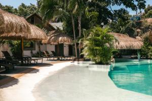 a pool at a resort with thatched umbrellas and chairs at Secret paradise moalboal in Moalboal