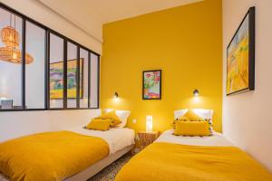 two beds in a room with yellow walls at LA CIGALE by K6 Conciergerie Prestige in Cassis