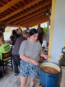 een vrouw die naast een pot eten staat bij Mill House Apartment and Camping in Ljutomer