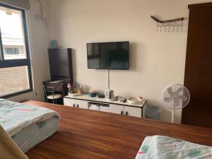 een slaapkamer met een flatscreen-tv aan de muur bij Dou Dou Long Homestay in Donggang
