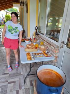 a woman standing in front of a table with food at Mill House Apartment and Camping in Ljutomer