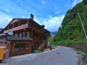a man standing in front of a wooden house at TRIA APART OTEL in Uzungöl
