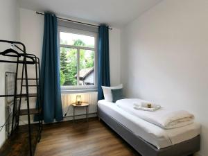 um quarto com uma cama e uma janela em BohnApartments - Stadtblick Zechenhaus - Balkon - gratis Parkplatz - WLAN - sehr ruhig - barrierearm em Ilmenau
