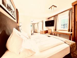 una camera da letto con un grande letto bianco e una televisione di Hotel Das Urbisgut a Altenmarkt im Pongau