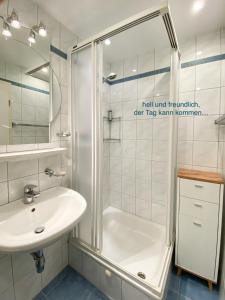 uma casa de banho branca com um chuveiro e um lavatório. em Whg Sturmmöwe - Haus Nordlichter em Wendtorf
