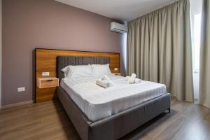 een slaapkamer met een groot bed met witte lakens bij ApartHotel EDA in Durrës