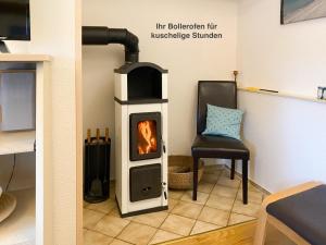 a wood burning stove in a living room with a chair at Whg Falckenstein - Haus Nordlichter in Wendtorf