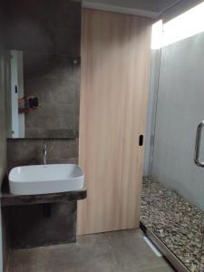La salle de bains est pourvue d'un lavabo blanc et d'une douche. dans l'établissement Lynn Resort Carita, à Sukarame