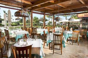un restaurante con mesas blancas, sillas y sombrillas en Puerto Anfi- Luxury- Penthouse- Sleeps 9- Amazing Sea Views en Mogán