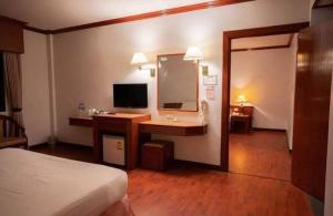 Habitación de hotel con cama y escritorio con espejo. en โรงแรม เพนท์เฮ้าส์ รีสอร์ท เบตง, en Betong