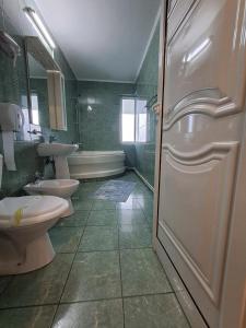La salle de bains est pourvue de 2 toilettes, d'un lavabo et d'une baignoire. dans l'établissement Hotel Green House, à Craiova