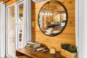a mirror on a wall next to a table with books at Knotty Pines 4 Bedroom with Waterfront Views in Chelmsford