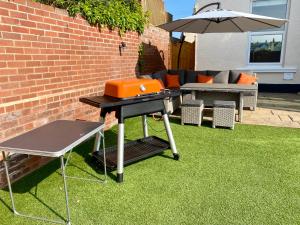 a barbecue grill on a lawn with an umbrella at Dog friendly home close to the beach and the town in Exmouth