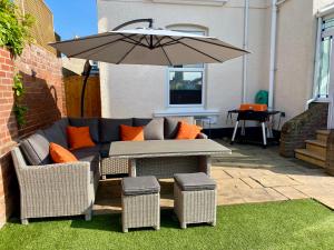 a patio with a couch and a table with an umbrella at Dog friendly home close to the beach and the town in Exmouth