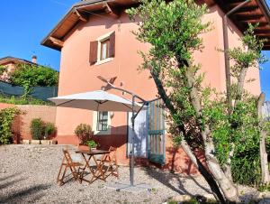 uma mesa e um guarda-chuva em frente a uma casa em Casa vacanze Monte Galetto em Bussolengo