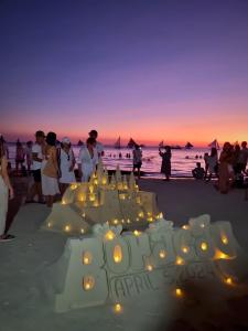 een groep mensen die rond een verjaardagstaart op het strand staan bij Nirvana Beach Resort in Boracay