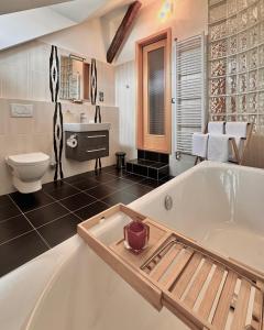ein großes Bad mit einer Badewanne und einem WC in der Unterkunft Apartmány Bašta & Wellness in Sušice