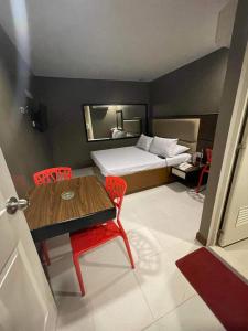 um pequeno quarto com uma cama, uma mesa e cadeiras em Hotel Sogo Edsa Cubao em Manila