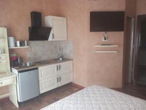 a kitchen with white cabinets and a sink and a bed at Lussuoso B&B in Palmi