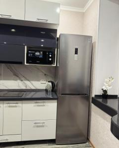 a stainless steel refrigerator in a kitchen with white cabinets at 2-ух комнатная люкс квартира in Balqash