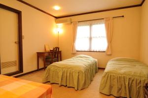 1 dormitorio con 2 camas y ventana en Pension Syo, en Hakuba