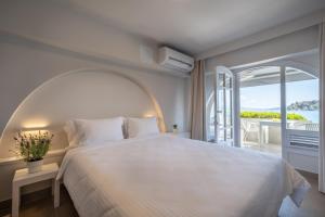 a bedroom with a large white bed and a balcony at Nelly's Apartments in Tolo