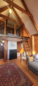 a living room with a couch and a staircase in a house at The Ponderosa Cabin. in Jindabyne